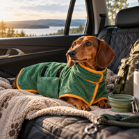 Small dog wearing a green Pawsmee quick-dry robe while relaxing on the back seat during a road trip